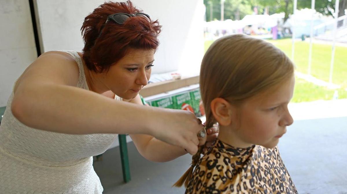 Desiree Stitzer, of Holiday Hair salon, cuts a 10-inch braid from Ann Weikert to be donated to Pantene hair donations on the grand stand of the Grange fairgrounds during the Happy Valley Relay for Life on Saturday.