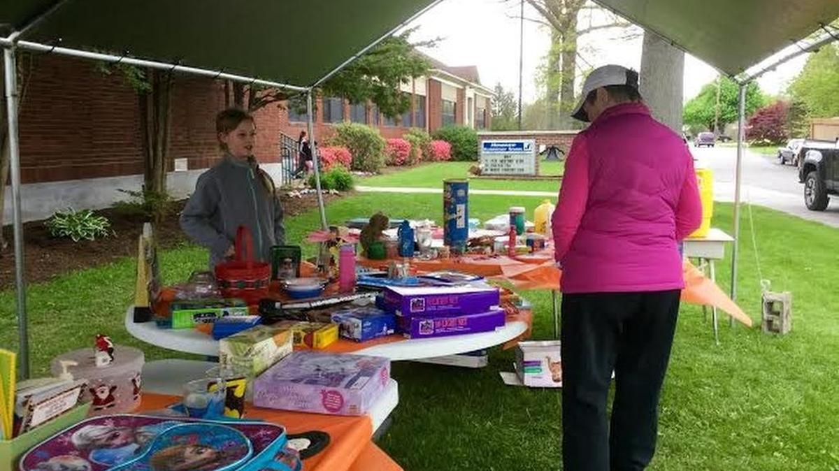 Howard Elementary School fifth-grader Ember Herr helps customer Kathleen Danly during the school’s yard sale. The sale was set up outside of the school’s main entrance Friday to help raise money for the Make-A-Wish foundation.