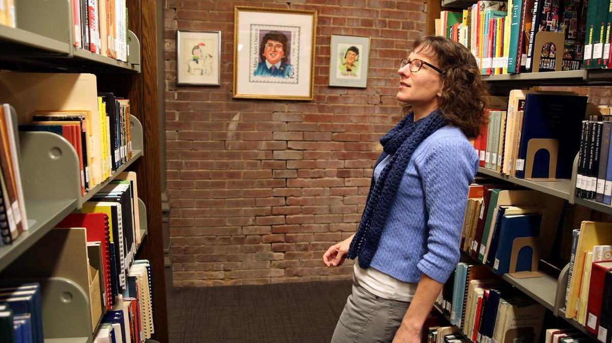 Director of Information Services Tara Murray scans the shelves of stamp books at the American Philatelic Society Library in Bellefonte.