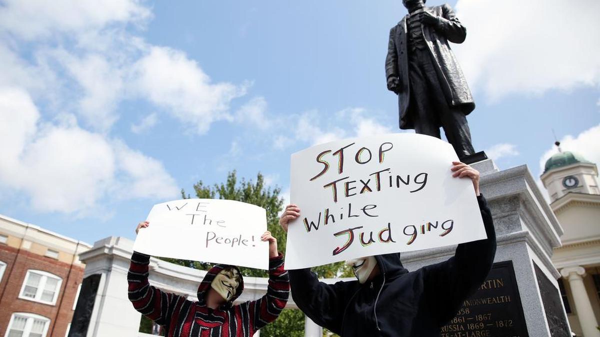 “Anonymous” protestors demonstrate in front of the Andrew Curtin statue in front of the Centre County Courthouse in August.