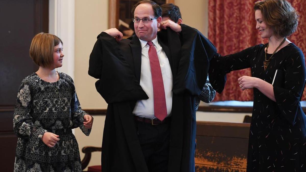 Brian Marshall puts on his robe after being sworn in during the swearing in ceremony Friday at the Centre County Courthouse.