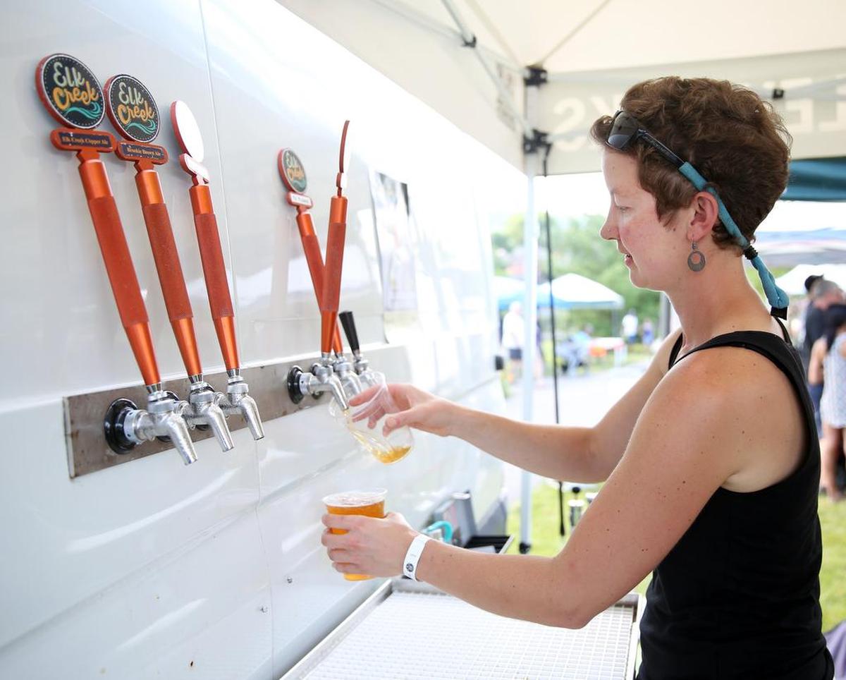 Genny Uhl, of Elk Creek Cafe, pours a beer during Summer Craft Beverage Expo Sunday, June, 18, 2017, at Talleyrand Park in Bellefonte.