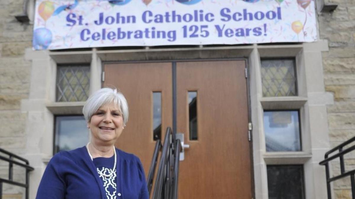 Linda Plozner poses outside of St. John Catholic School in Bellefonte, which is celebrating 125 years. Plozner and multiple generations of her family have attended the school.