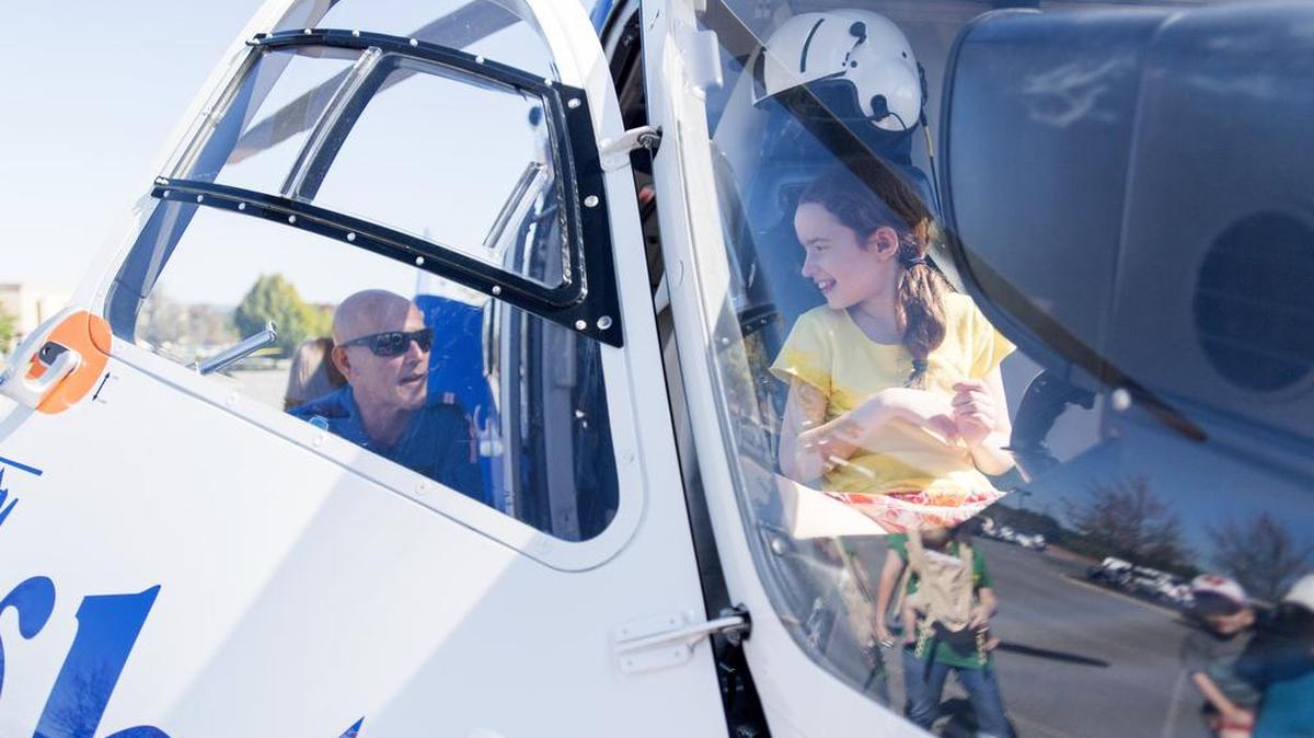 Life Flight pilot Jim Stine talks to Julianna Kellerman, 10, as she sits in the cockpit of the helicopter during the Patton Township Children’s Fair on Saturday in the Wegman’s and Target parking lot.