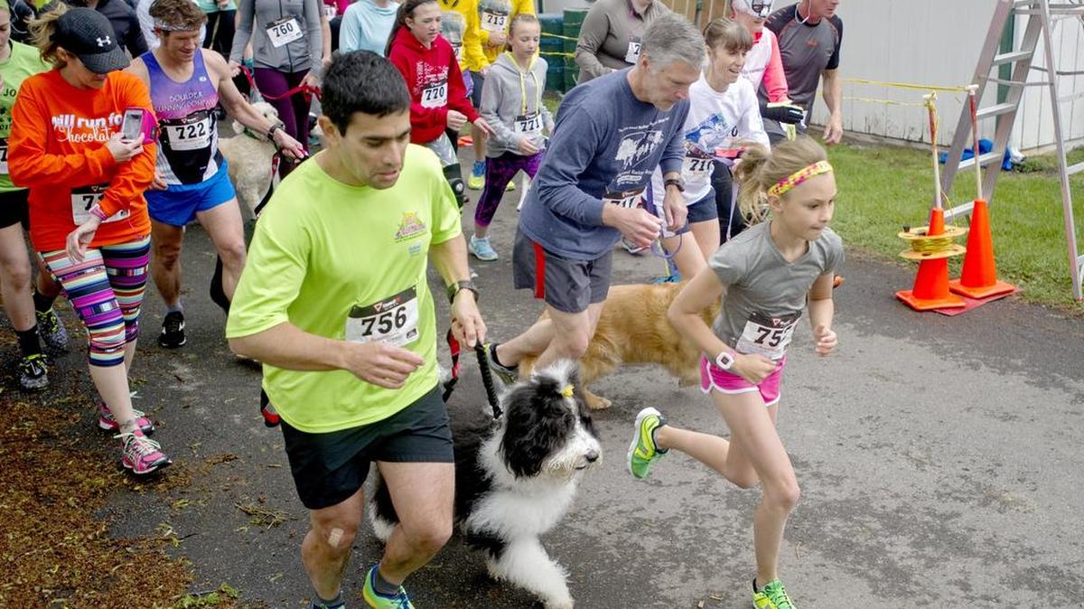Marlee Kwasnica, 11, darts from the starting line with her dad, Tony, and dog, Penny, during the 8th annual Dog Jog benefiting Pets Come First on Saturday at the Grange fairgrounds. Penny, a sheepadoodle, wanted to run alongside Marlee for the race.