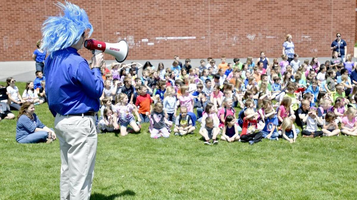 Centre Hall principal Kurt Nyquist wears a blue wig to kiss a goat after the students raised $4,000 for their Walk-a-Thon.