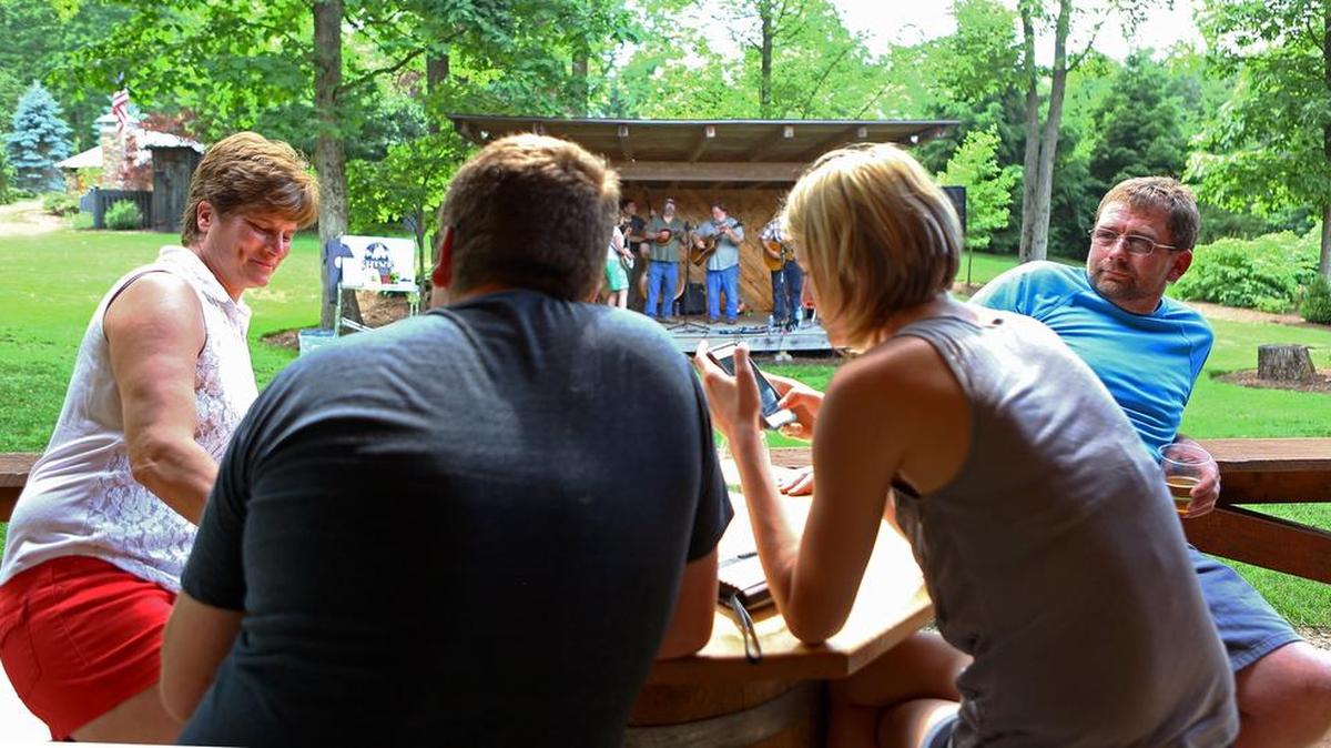 Matt Carney, far right, sits with his family as the Tussey Mountain Moonshiners perform during the Father’s Day barbecue at Seven Mountains Wine Cellars on Sunday.