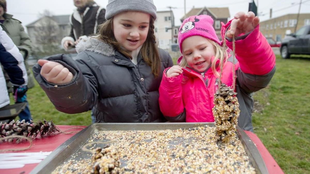 Jocelyn Wilson, 5, and her sister Jordana, 4, roll pinecones in peanut butter and bird seed to hang on the community tree on Pine Street during the Philipsburg kick off to Christmas on Saturday. Several local churches came together this year for the tree that youngsters could help to decorate.