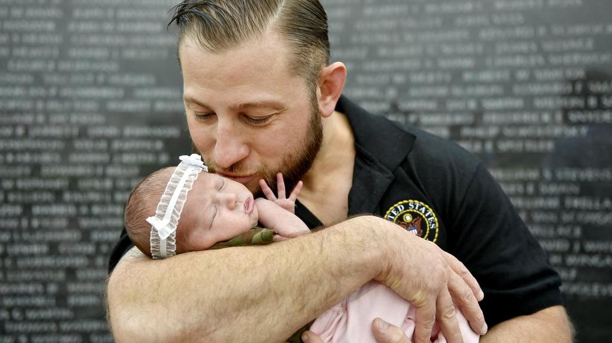 Eric Frick kisses his week-old daughter Gabbie on Sunday,. Frick left college to enlist in the army after the 9/11 terrorist attacks.