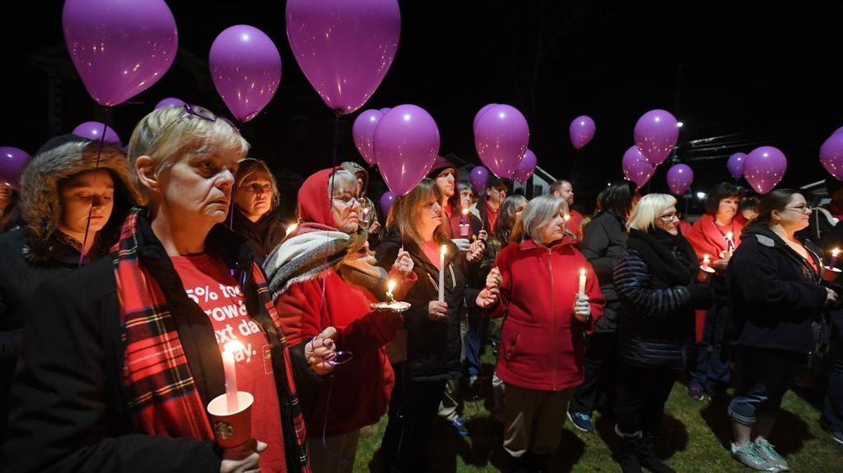 People hold candles and purple balloons before the balloon release during a candlelight vigil for the Schultz family Monday at Osceola Mills Community Park.