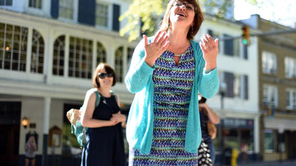 Lori Pacchioli, director of advancement for State College Friends School, sings a song about peace with a group of students on the International Day of Peace in downtown State College on Wednesday.