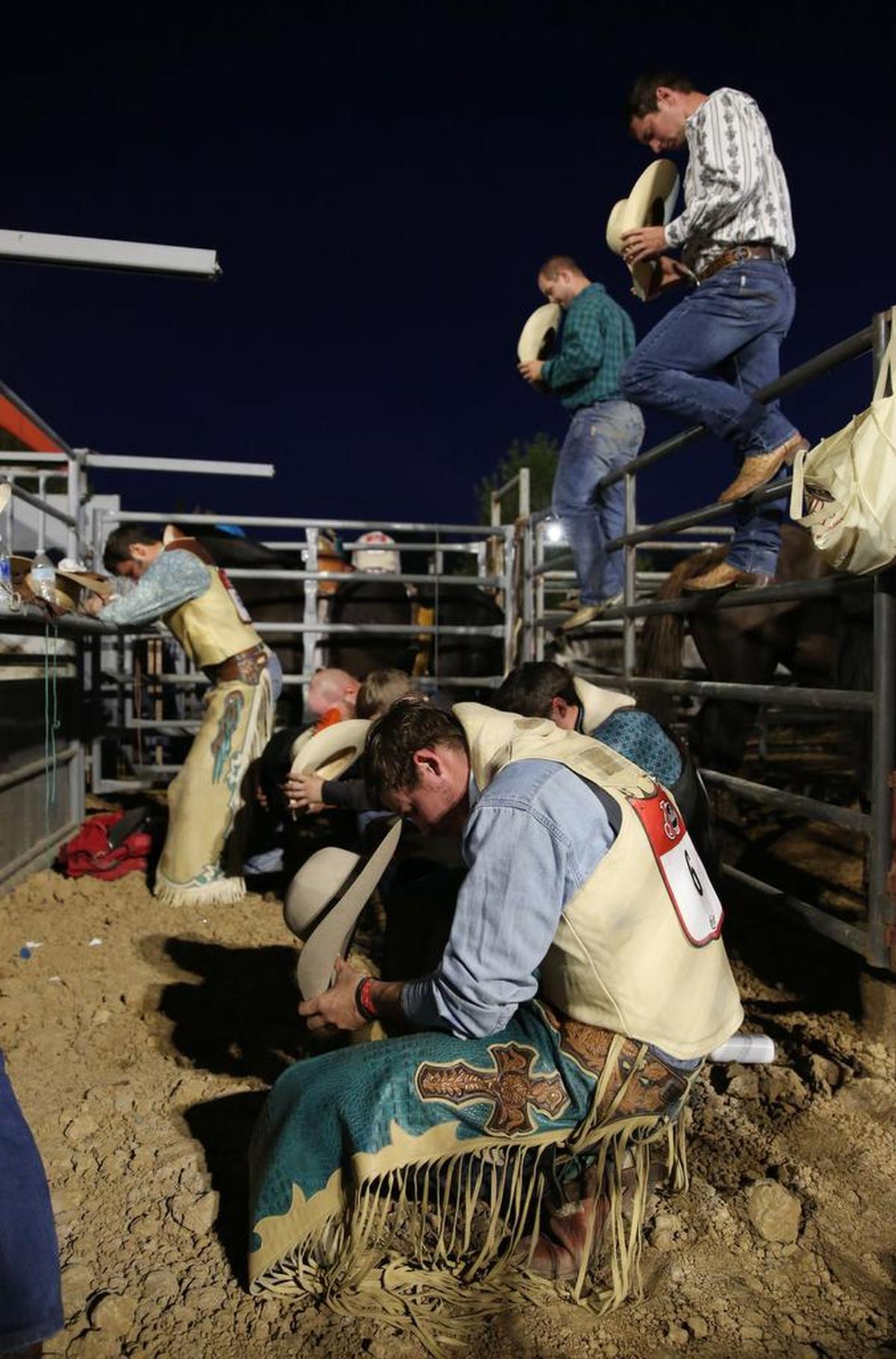 Riders take a moment to bow their heads during a prayer at the Coy Lutz Memorial Rodeo in September 2017 at Grange Park.