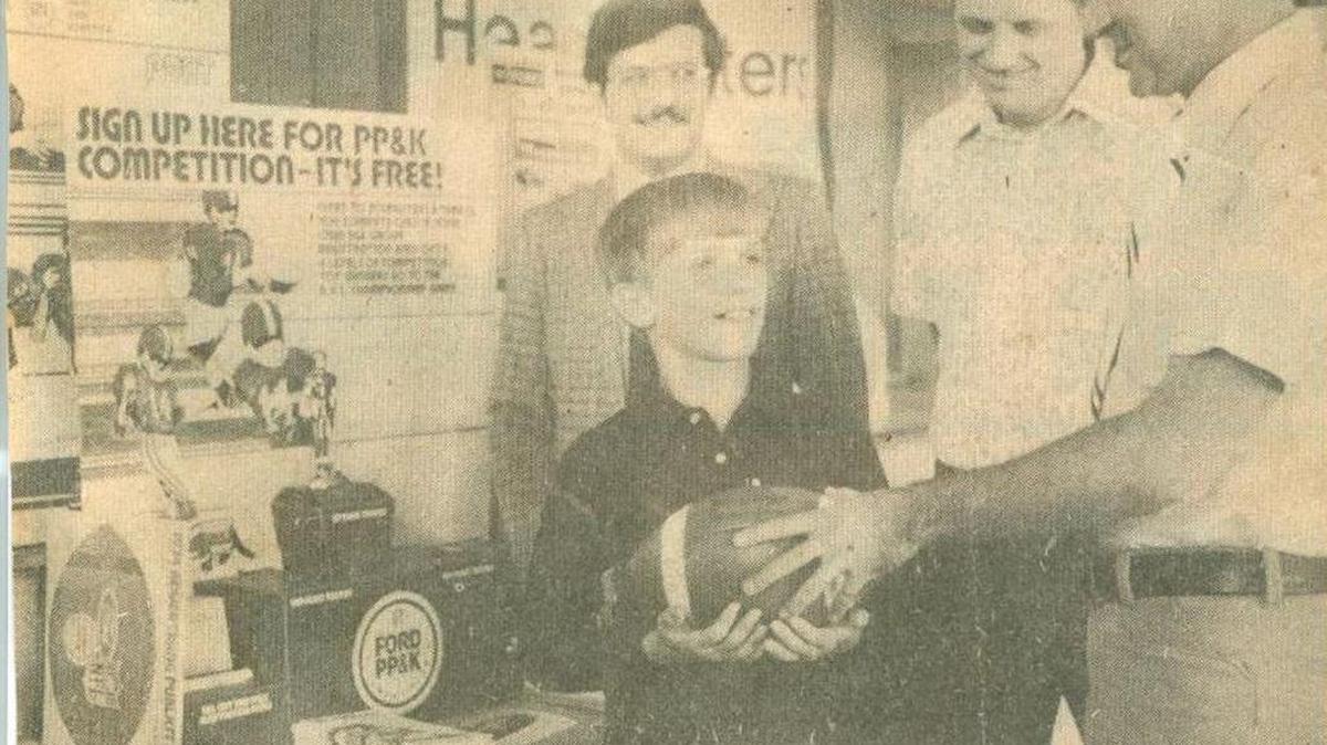 Chris Miller accepts a football from Chuck Witmer, Punt, Pass and Kick contest chairman for the Bellefonte Area Jaycees.