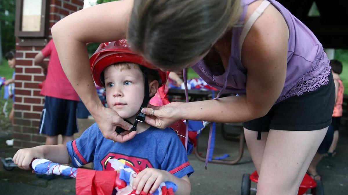 Christa Jodon helps her son, Ethan, 3, with his helmet Monday during bike decorating for the Kids on Wheels Parade at Holmes Foster Park in State College. Line-up for the parade begins at 9:30 a.m. Tuesday, with step off at 10. It starts at the corner of Locust Lane and Foster Avenue.