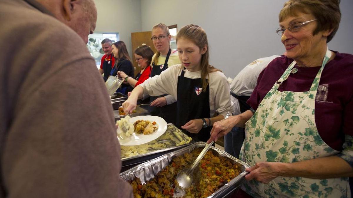 Betsy Llewellyn, right, and Madeline Geduldig,12, serve food during a community Thanksgiving dinner on Thursday at St. Andrew’s Episcopal Church.