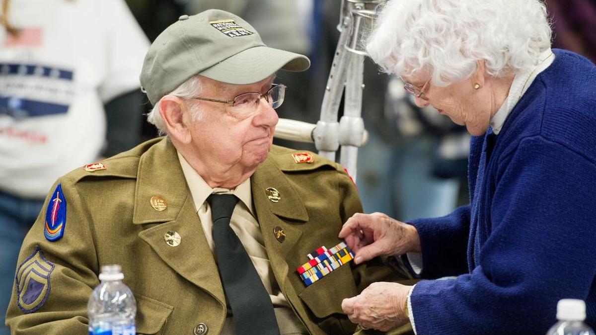 Army veteran David Rhoades smiles as his wife straightens his medals during the Military Appreciation Day tailgate at the Bryce Jordan Center on Saturday. Rhoades served from 1949-1952.