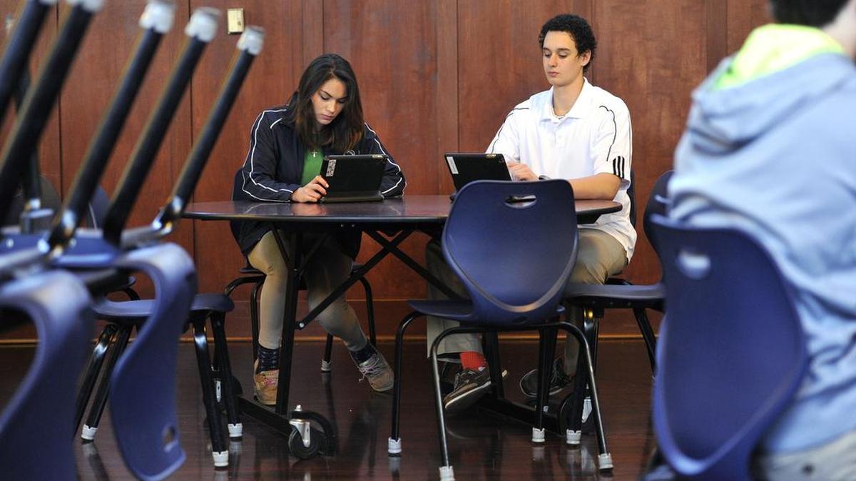 Tenth-graders Ana Legaspi and Bryce Herman do work on their iPads. Every student at St. Joseph’s Catholic Academy in Boalsburg has an iPad with the app eBackpack on it Feb. 26, 2016. The app allows students to get assignments and do work both at school and at home.