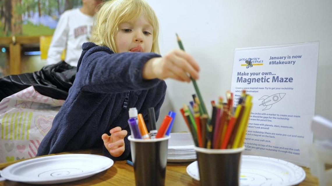 Lisel Perles, 5, chooses a colored pencil to create her magnet maze at the Discovery Space of Central Pennsylvania in downtown State College on Saturday. The maze is made using magnets on either side of a paper plate that guides a rocket ship through the children’s drawings.