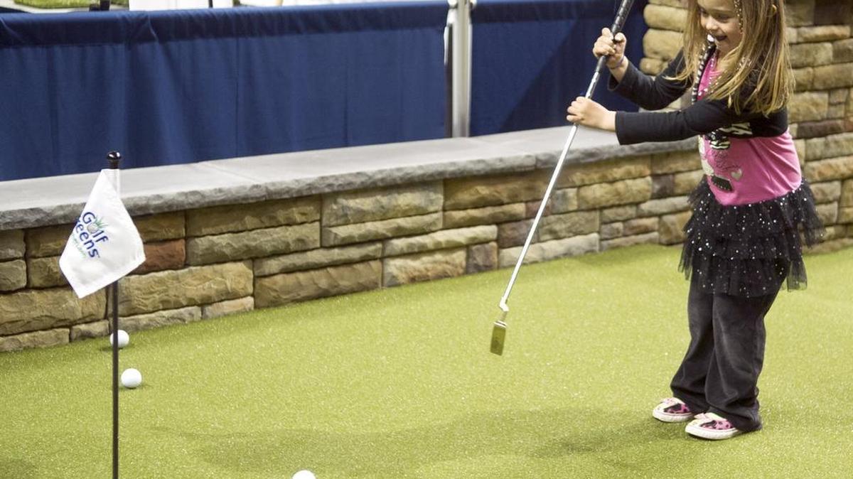 Avalyn Belinda, 4, putts on a fake golf green set up by Forever Lawns during the Home and Garden Show Friday at the Bryce Jordan Center. The show wrapped up Sunday.