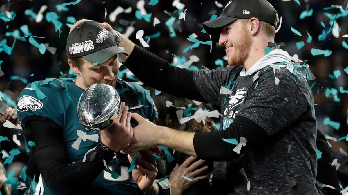 Philadelphia Eagles quarterback Carson Wentz, right, hands the Vincent Lombardi trophy to Nick Foles after winning the NFL Super Bowl 52 football game against the New England Patriots, Sunday, Feb. 4, 2018, in Minneapolis. The Eagles won 41-33.