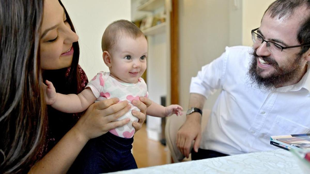 Miri Rabbi Hershy Gourarie laugh with their 3-month-old daughter, Mushka, in their home on Thursday.
