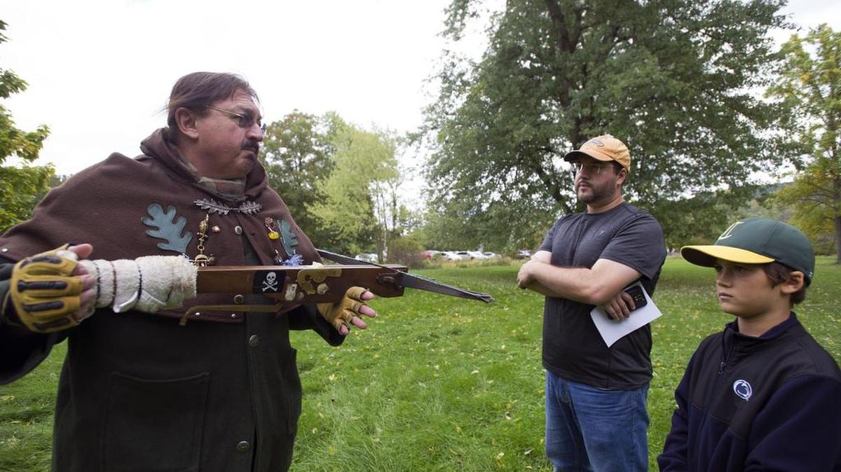 Dennis Greenaway, left, shows Nathan Elliott and Tiernan Elliott a crossbow during the Old World Festival Sunday at the Boal Mansion.