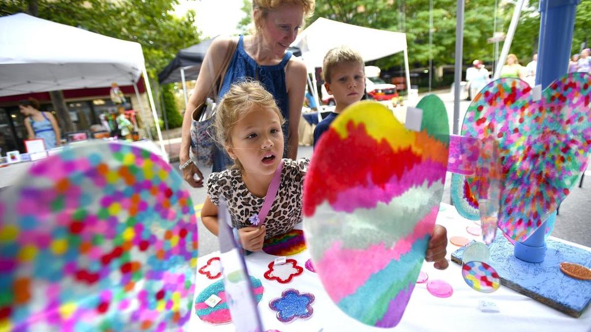 Tami Mizikar looks at sun catchers by Olivia Bickle with her niece Maren Moenssens and nephew Maerek Moenssens. Wednesday is Children and Youth Day at the Central Pennsylvania Festival of the Arts in State College.