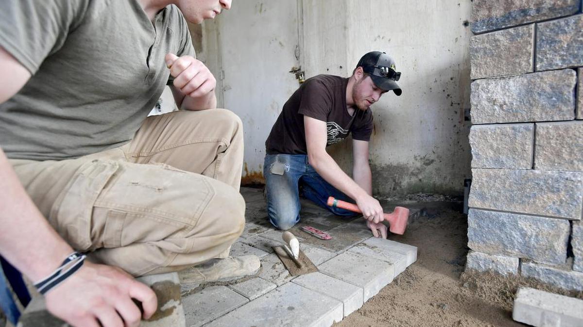 Ketan Kriefski watches as Mason Schnabel places a paver on the new back patio of the Stormbreak House. Students from the College of Agricultural Sciences are creating a patio and landscape at Stormbreak.