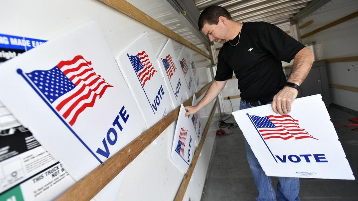 Dusty DeVinney loads “vote” signs into a truck on Monday to be taken to a precinct.