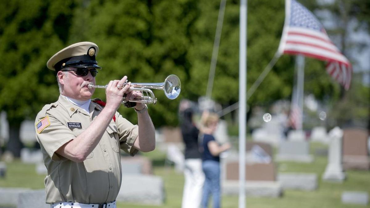 Dave Strouse plays trumpet as community members simultaneously raise 50 American flags in the Pine Hall Cemetery to start the Memorial Day service hosted by the American Legion Post 245 in 2015.