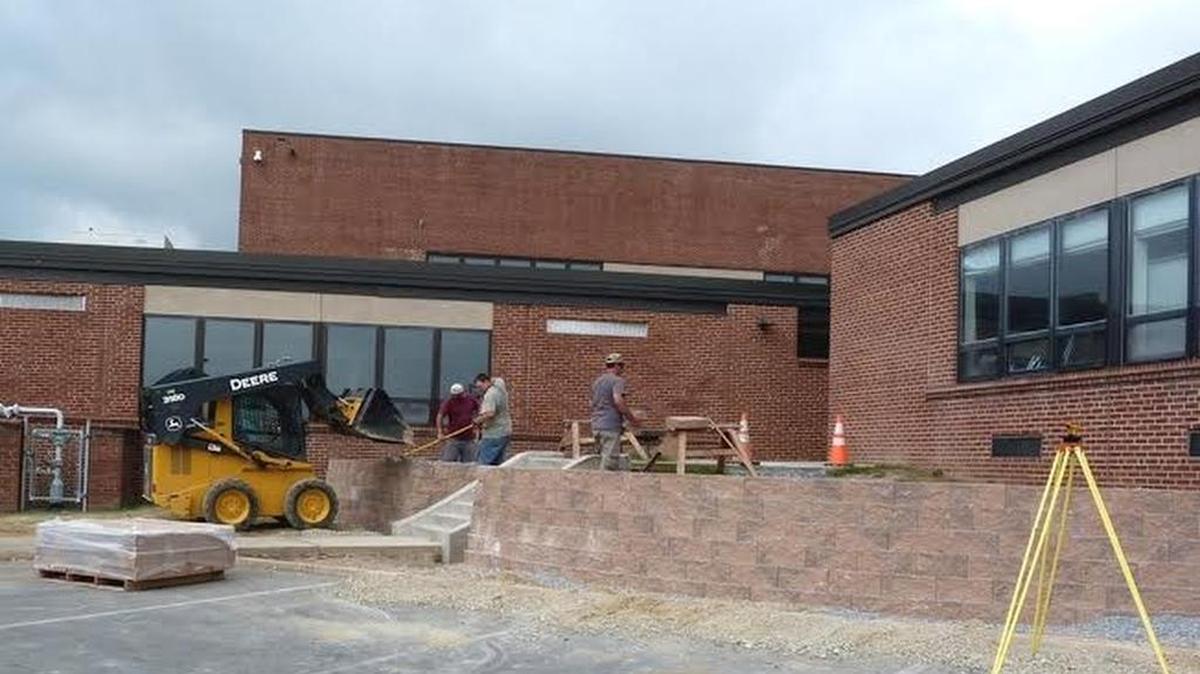 Bald Eagle Area School District maintenance workers remove steps and railing at the high school that were deemed unsafe. Randy Greene, John Schmoke, Keith Hoffman and Brian Phillips fill the cores of a block wall on the steps and retaining wall at the entrance near the receiving room at the high school. Landscaping and lighting will follow.