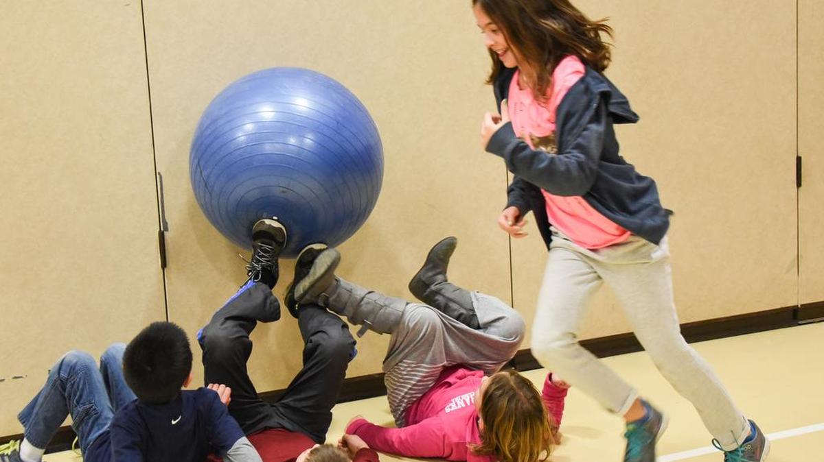 Gabi Todd runs past Mary Ledney, Evan Baxter and Brandon Zhang as they pass the exercise ball to each other using their feet during the physical education component of CEEL.