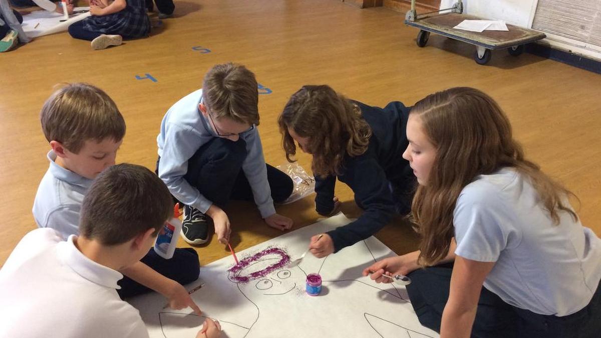 Faith Family members work together to add glitter to their angel decoration, which was used to decorate the school for Christmas.