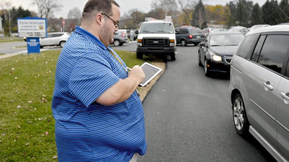 Bill Ewing checks-in cars as parents arrive after school to pick up their kids. Young Scholars of Central Pennsylvania is using the mobile app PikMyKid to help organize dismissal and make sure each kid is accounted for.