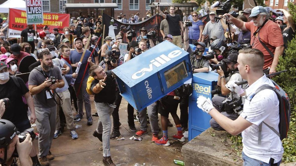 White nationalist demonstrators clash with a counter demonstrator as one throws a newspaper box at the entrance to Lee Park in Charlottesville, Va., Saturday, Aug. 12, 2017.