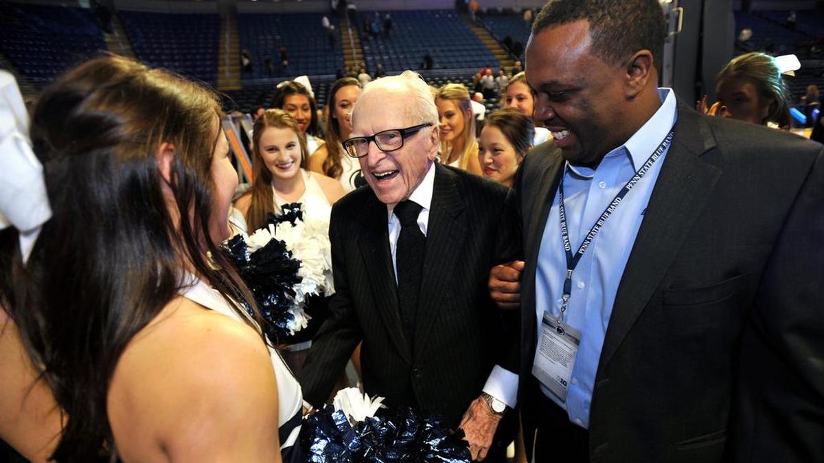 Ray Walker, center, and Penn State Blue Band Director Gregory Drane talk with cheerleaders after Walker led the alma mater at the Penn State vs. Nebraska basketball game in February. Walker is the oldest Penn State alumni at age 103, having graduated in 1935.