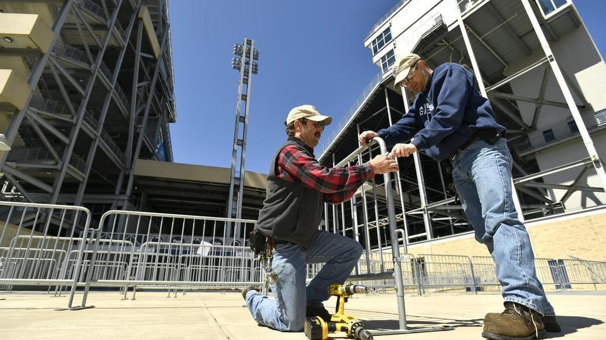 Phil Williams, left, and Steve Hugar, with Penn State Office of Physical Plant, place gates outside Beaver Stadium for the autograph session. Preparations are underway on campus for Saturday’s Penn State football Blue-White game.