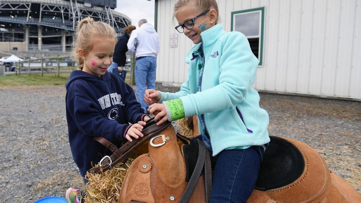 From left, Riley Kocher, 5, and Molly Staniar, 8, play on a horse saddle during an open house at Penn State’s “Old Barn” across from Beaver Stadium on Saturday.