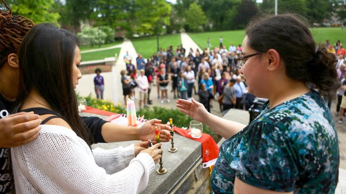 Lianne Luu, left, and Lia Talmas light candles on the steps of Old Main on Monday to start the candlelight vigil honoring the victims of the Orlando shooting.