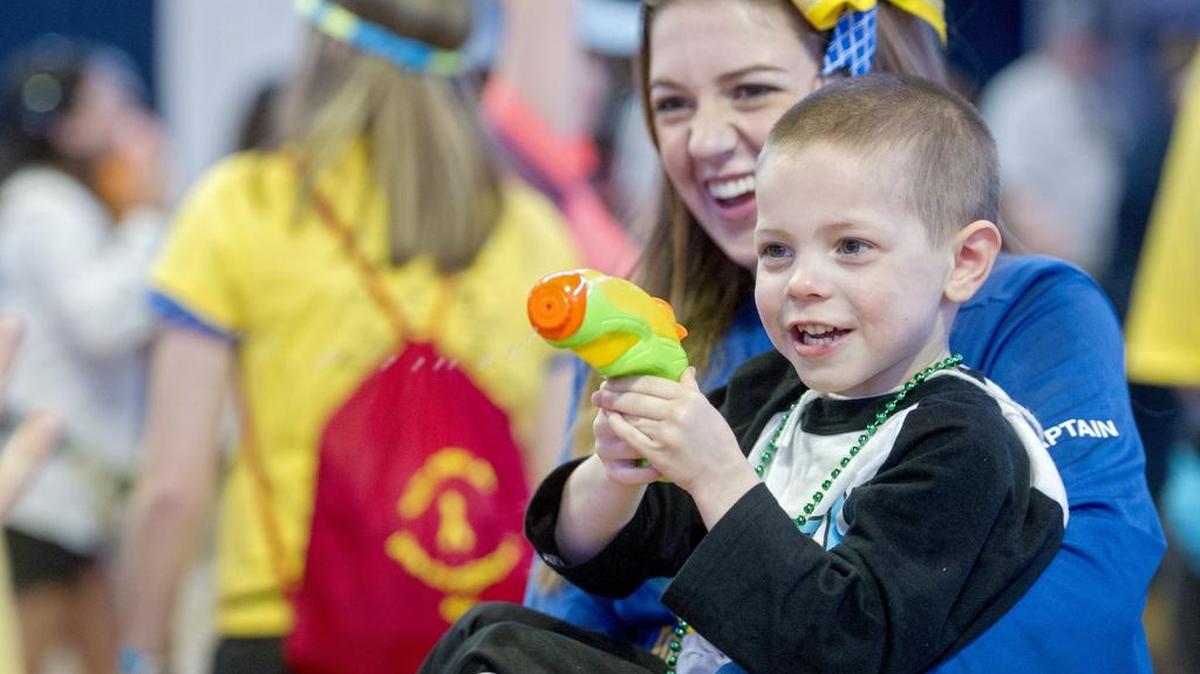 Katie Welliver carries Lucas Knaper, 4, as he squirts anyone who passes by during the Penn State IFC/Panhellenic Dance Marathon on Saturday, February 20, 2016, at the Bryce Jordan Center.