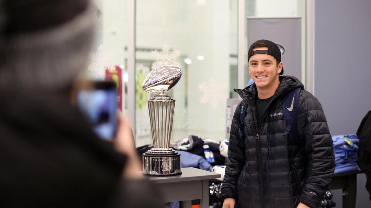 Penn State freshman Grace Leibow takes a photo of freshman Brett Davis next to the Leishman Trophy on Monday in the Penn State Book Store at the HUB-Robeson Center.