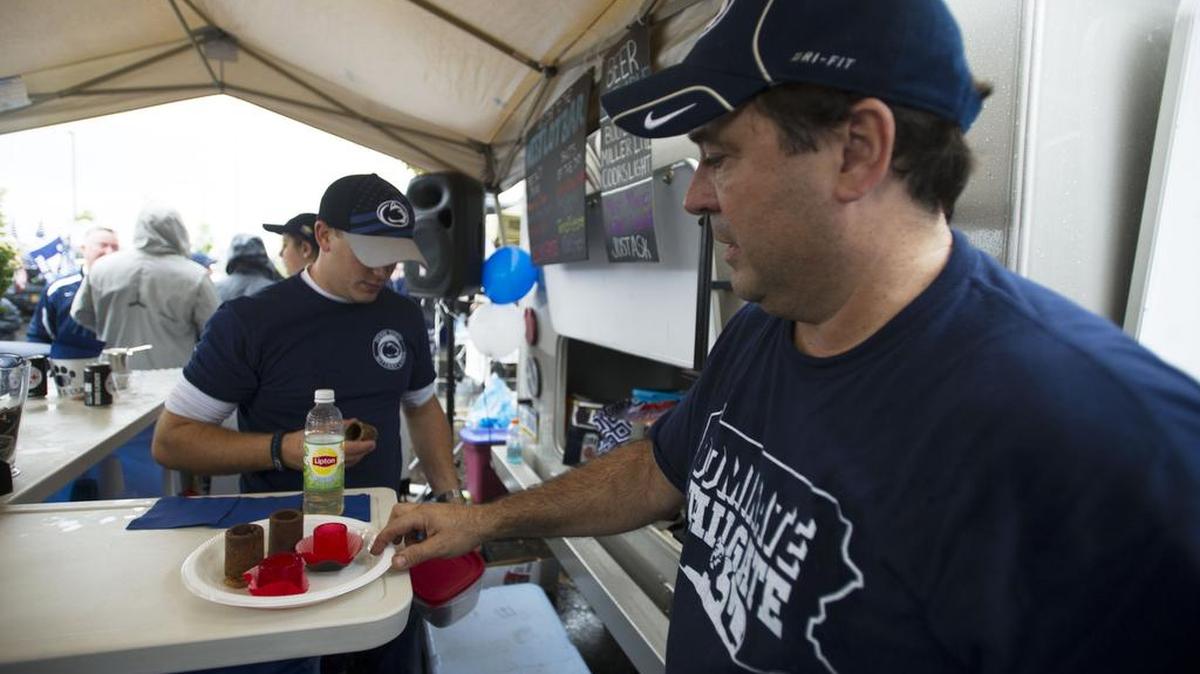 Gus San Roman, right, of Penn State Broad Top Area Tailgate Society, shows off some edible shot glasses before a previous Homecoming game.