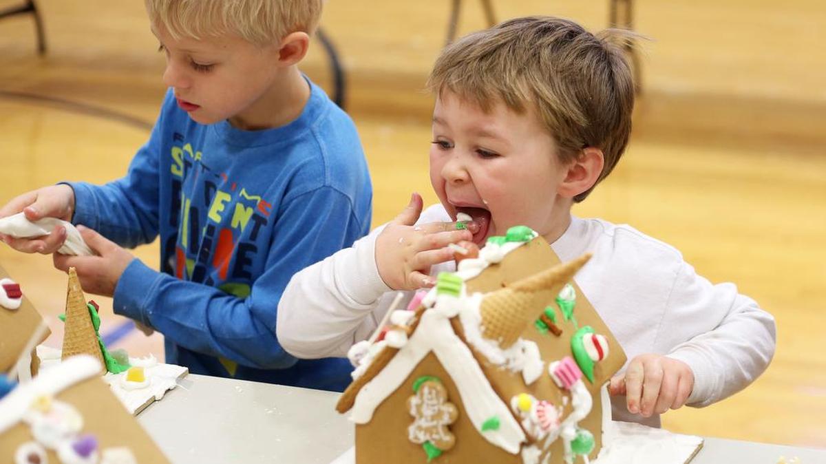 Dakota Pollock, left, licks the frosting from his fingers as Parker Nye decorates his gingerbread house on at Centre Hall-Potter Elementary School.