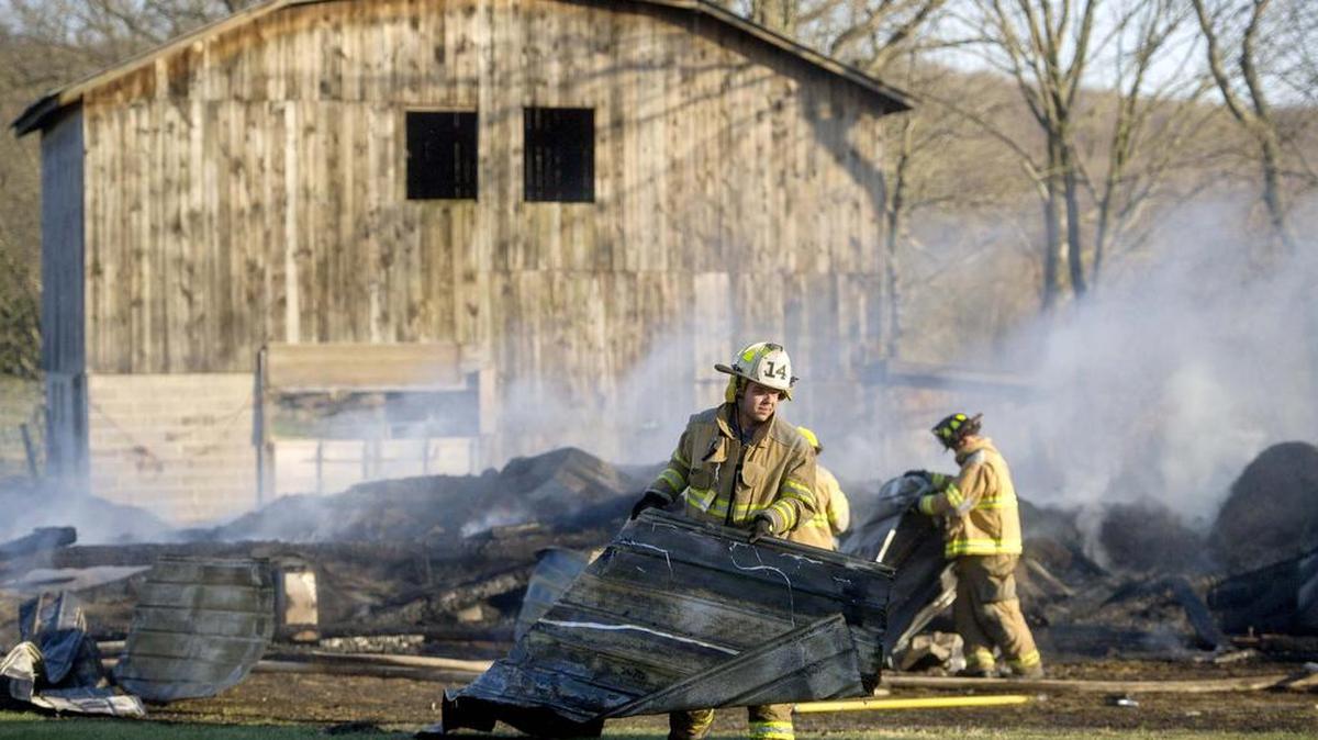 Howard Fire Company firefighter Tyler Penland pulls a piece of debris away from a corn crib full of hay that completely burned on Shay Lane in Marion Township on Saturday, April 16, 2016.