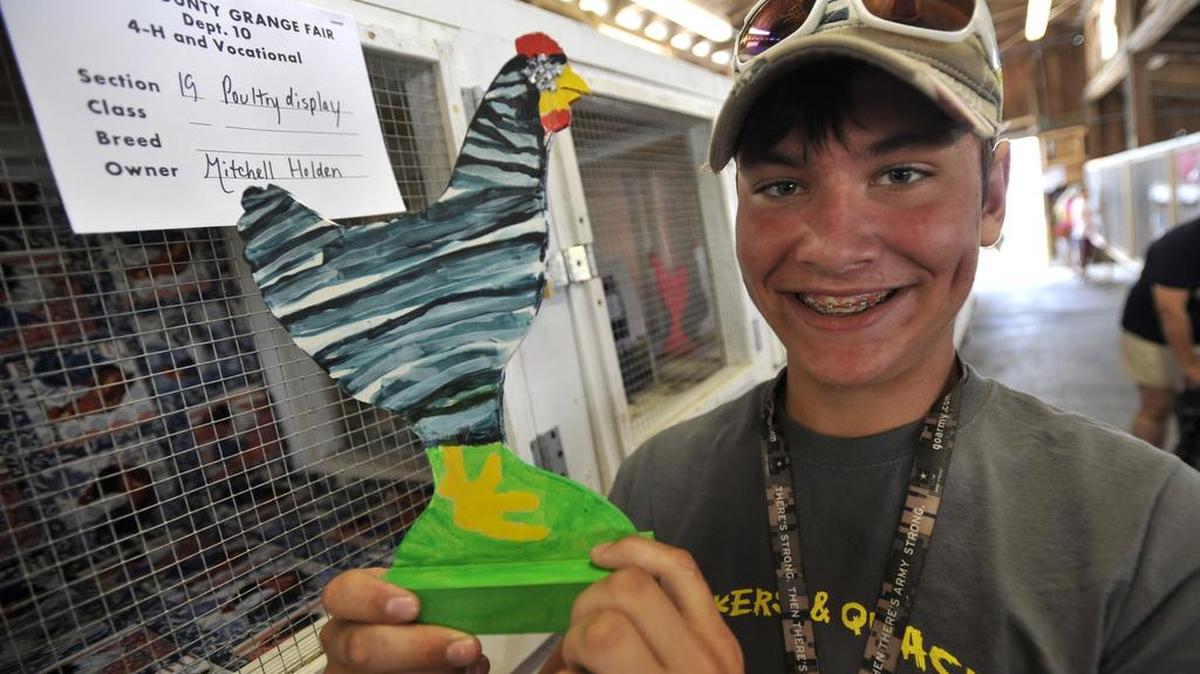Mitchell Holden, 13, of Howard, holds a wooden chicken he painted to look exactly like his real chicken during last summer’s Centre County Grange Encampment and Fair. Live poultry were not allowed at the fair because of the threat of avian flu. Contestants in the junior poultry showmanship competition had to give presentations without their chickens but many made wooden birds that they still kept in cages.