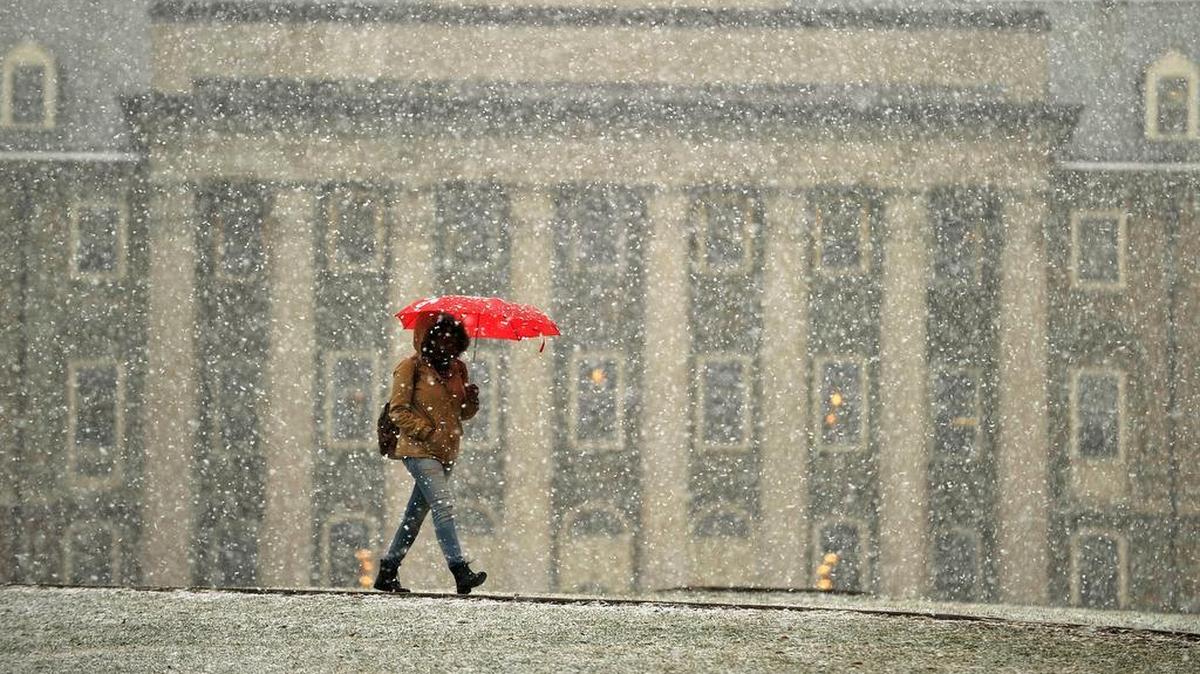 A pedestrian walks in front of Old Main as snow falls March 2015.