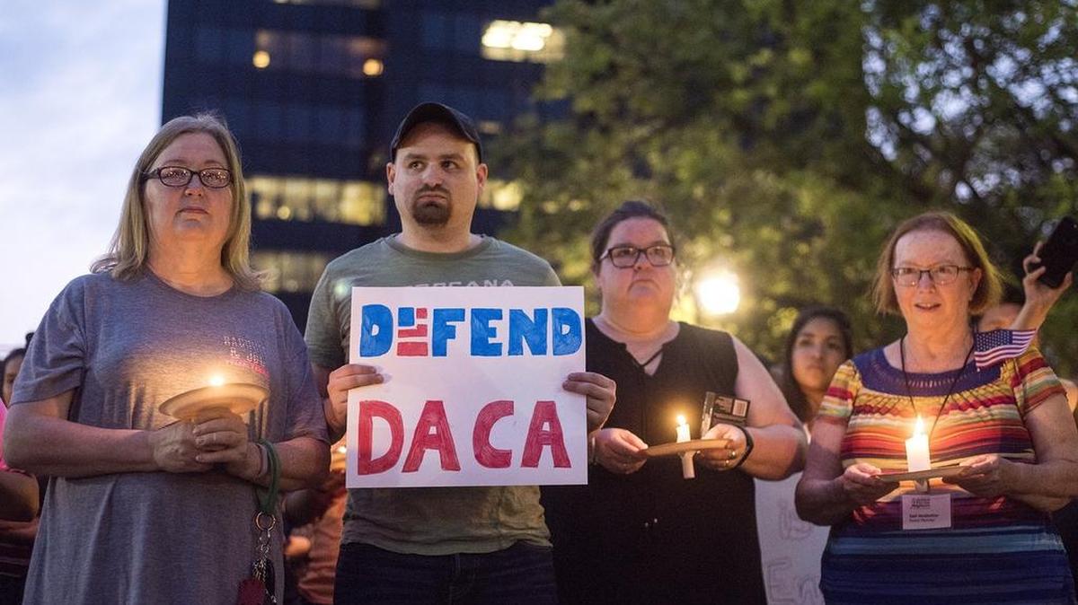 Martha Waggonner, Walker Waggonner, Katie Powell and Gail McGlothin stand in silence holding candles and signs during a silent vigil in honor of Deferred Action for Childhood Arrivals at T.B. Butler Fountain Plaza in Tyler, Texas, on Tuesday. Nearly 500 people attended the vigil on the day that the Trump administration announced that they would phase out the program.