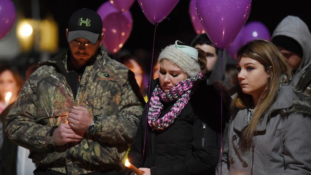 From left, Erik Daniels, Amber Blake and Paige Davis hold up candles during a candlelight vigil for the Schultz family Monday at Osceola Mills Community Park.