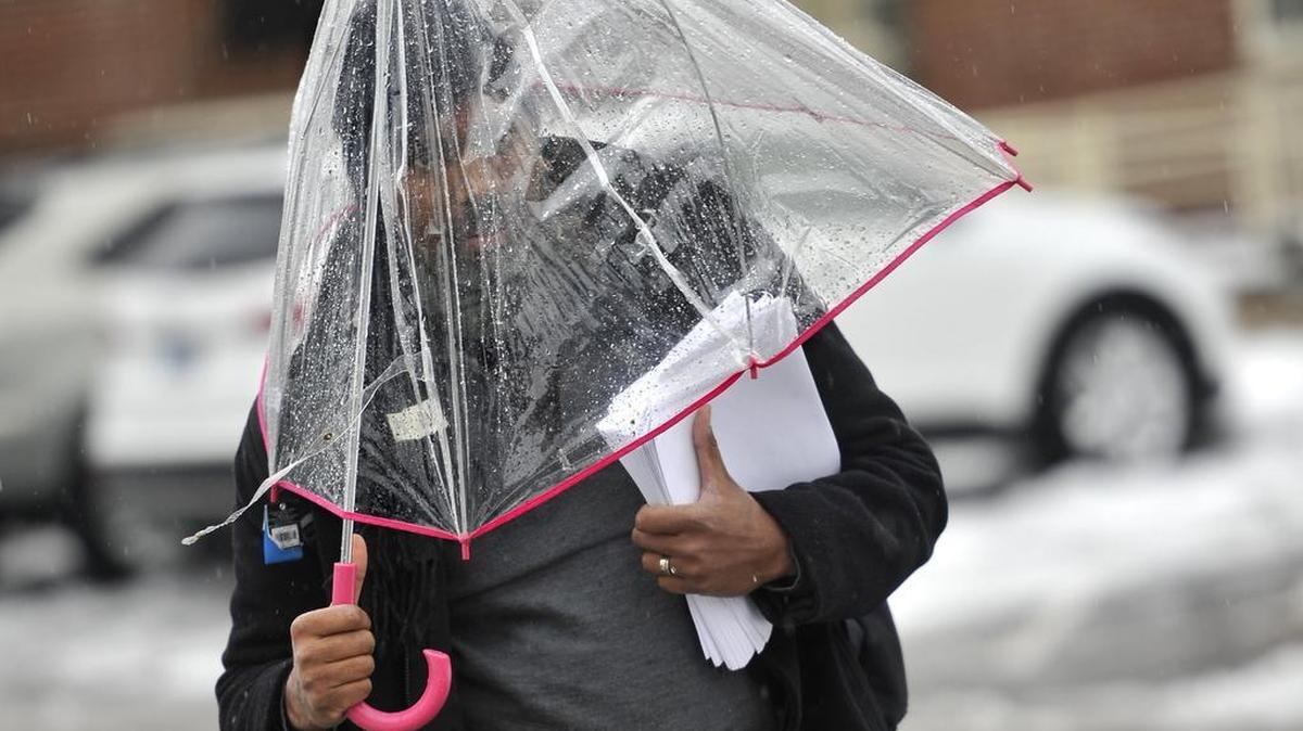 Penn State University professor Paris von Lockette walks to class using a broken umbrella on Tuesday.