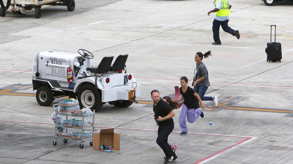 People take cover on the tarmac at the Fort Lauderdale-Hollywood International Airport onJan. 6, after police say Estaban Santiago opened fire near the baggage claim, killing five.